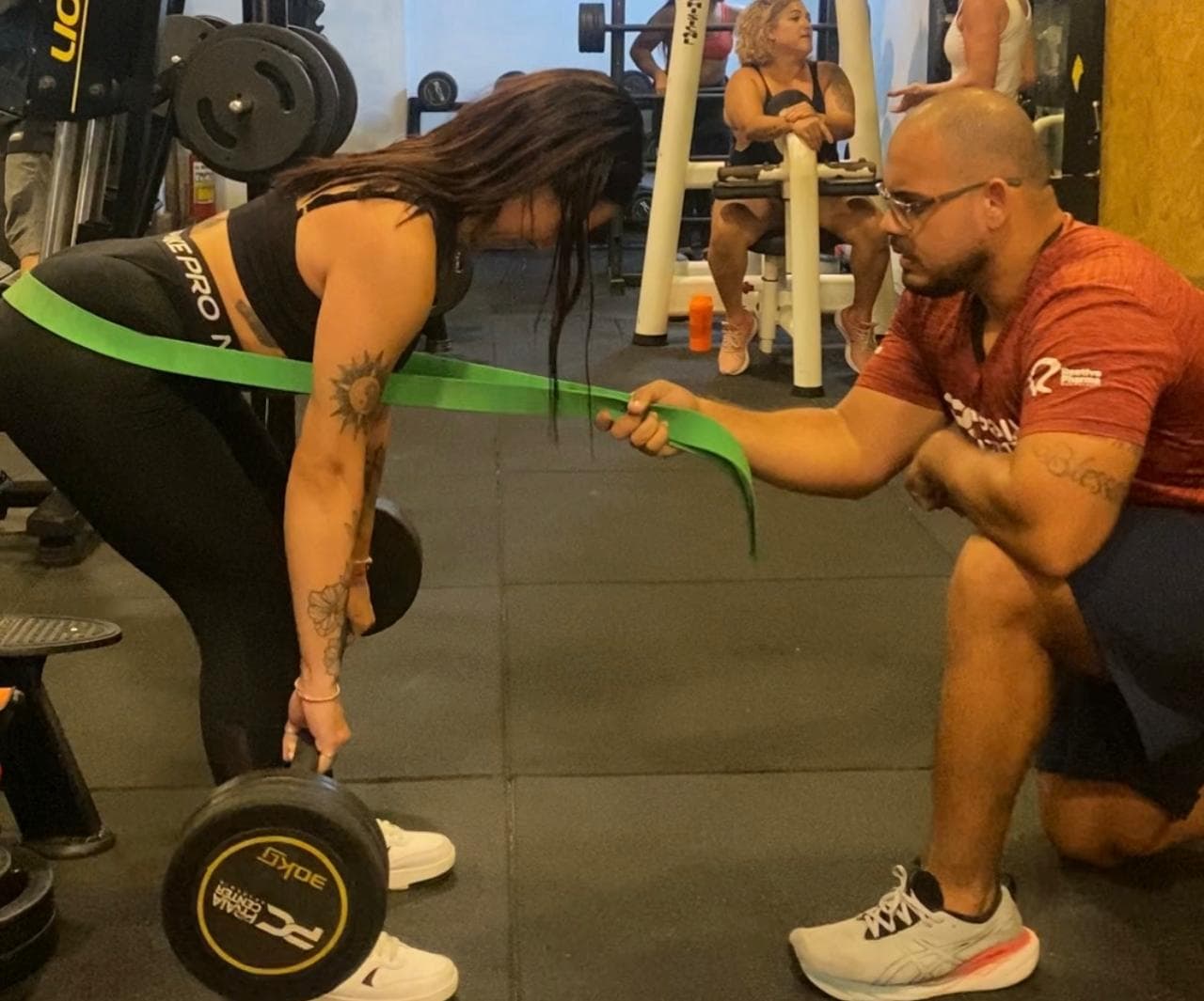 Brunno Neves acompanhando aluna em exercício com faixa elástica